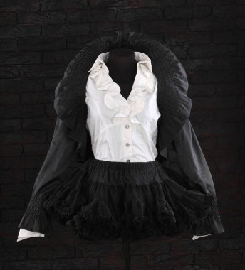 Siyah ceket ve mankenin üzerinde fırfırlar olan etek.