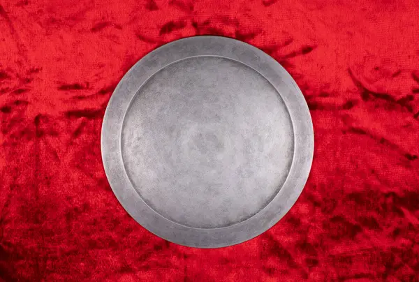 ancient round silver shield on a red background
