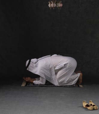 Arap adam diz çöküp dua ediyor.