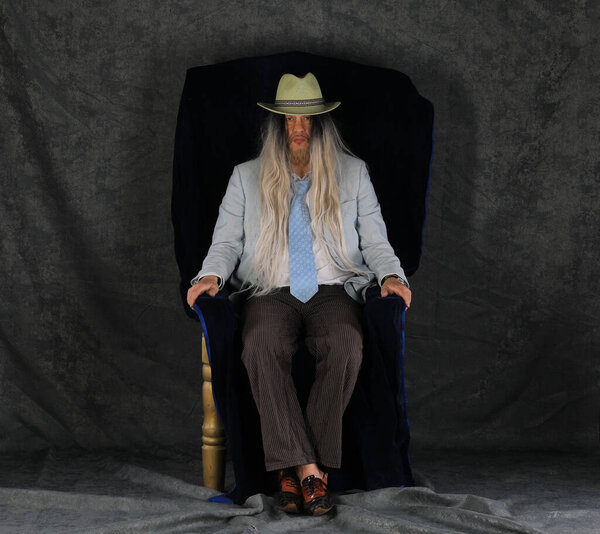 богатый старик бизнесмен сидит на стуле