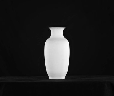 Beyaz klasik vazo, siyah arkaplanda kil sürahi.