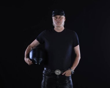 Siyah arka planda siyah elbiseli bir motorcunun portresi