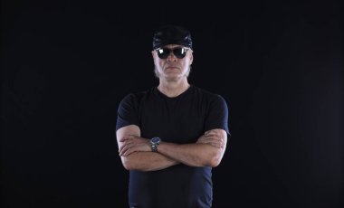 Siyah arka planda siyah elbiseli bir motorcunun portresi