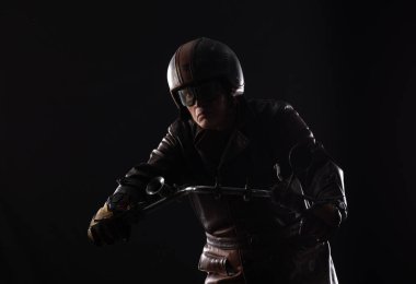 Siyah arkaplanda eski model bir motosikletçi portresi