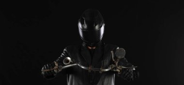 Siyah arka planda siyah elbiseli bir motorcunun portresi