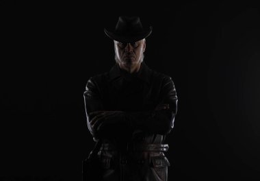 Siyah arka planda kahverengi deri ceketli yaşlı bir adamın portresi.