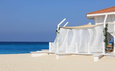 Beyaz kumlu sahil beldesi ve dinlenmek için bir çardak.