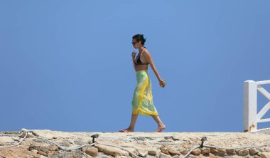  Mayolu güzel esmer kadın deniz kıyısında dinleniyor.