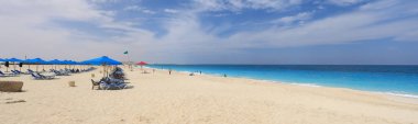  Sahilde beyaz kum ve şemsiyeli bir tatil köyü.