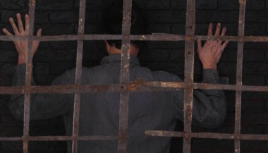 Mahkum sırtı hapishane hücresine dönük duruyor.