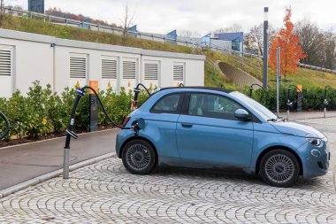 Almanya, Zusmarshausen 26.11.2022; Sortimo otobanı üzerindeki şarj parkında mavi bir Fiat 500e