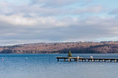 An old wooden footbridge with foliage leads into the Ammersee near Dieen in Bavaria 