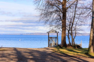 Gate with a weathered sign on the shore of Ammersee under trees in winter near Dieen in Bavaria 