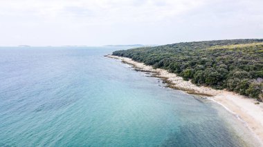 Rovinj yakınlarındaki Cisterna Sahili 'nde mavi denizli Rocky plajı.