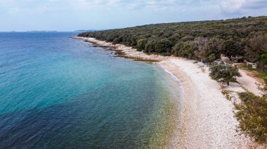 Rovinj yakınlarındaki Cisterna Sahili 'nde mavi denizli Rocky plajı.