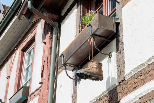 Two mountain boots hanging from a flower box at the window of an
