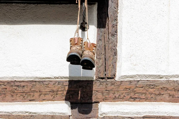 Two mountain boots hanging from a flower box at the window of an