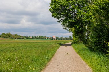 Augsburg yakınlarındaki Schmutter Vadisi 'nde yeşil çayırları ve sarı tecavüz tarlaları olan Hilly manzarası