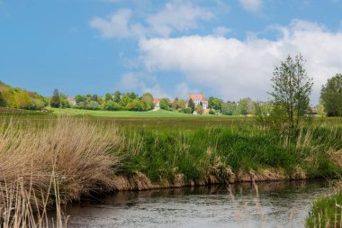 Augsburg yakınlarındaki Schmutter Vadisi 'nde yeşil çayırları ve sarı tecavüz tarlaları olan Hilly manzarası