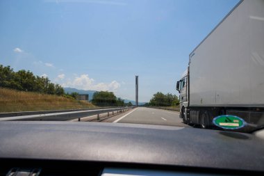 Çevresel yeşil rozetli hareket halindeki bir yolcu aracının ön camından otoyolu geçerken görüntüle