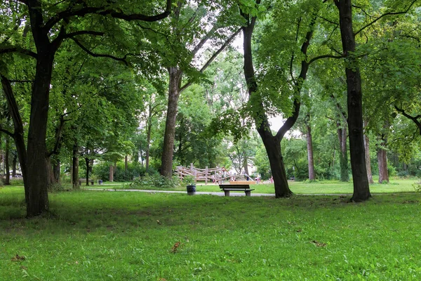 Almanya 'nın Augsburg kentindeki Grieslepark' ta bir çocuk parkının önündeki gölgeli ağaçların altında dinlenme tezgahı.
