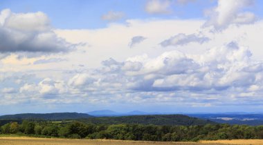 Arka planda dağlar ve mavi gökyüzünde beyaz bulutlar olan yaz manzarası