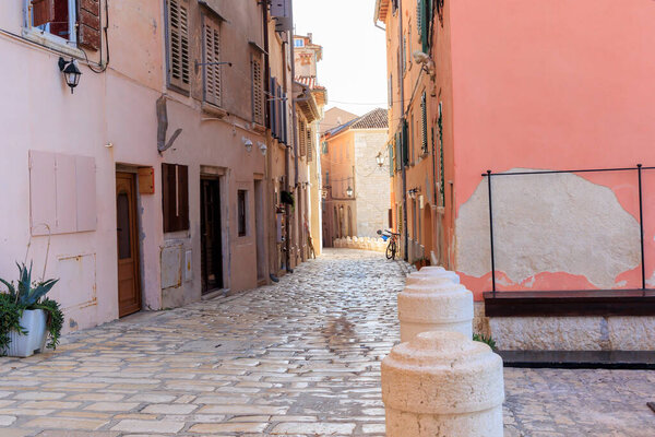 Old town alley in the Croatian town of Rovinj with old residential building fronts and freely laid power cables