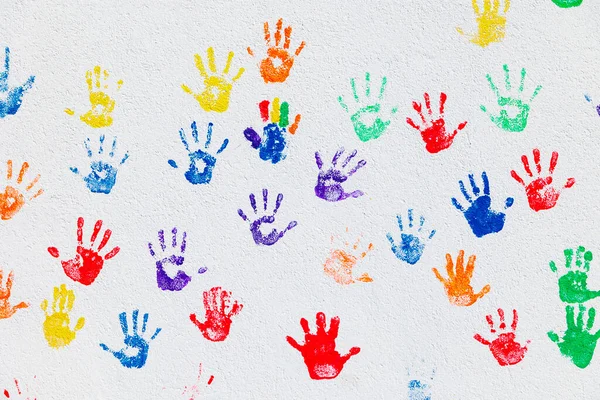 Pattern of colorful handprints was stamped on a white wall with colored children hands