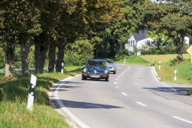 Fuggerstadt Classics, Almanya, Augsburg, 24 Eylül 2023 'te düzenlenen klasik araba rallisi sırasında, 70' lerden kalma Yeşil Jaguar E-Type, Blumenthal Kalesi yakınlarında bir kır yolunda sürüyor.