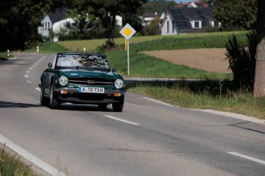 Klasik araba rallisi Fuggerstadt Classics, Almanya, Augsburg, 24 Eylül 2023 'te Blumenthal Kalesi yakınlarındaki bir kır yolunda yapılan yeşil Triumph TR6.