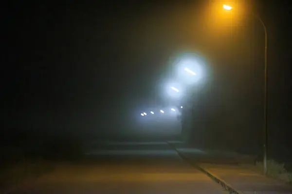 夜幕降临时 大雾中的街灯下 一条路通向地平线 — 图库照片