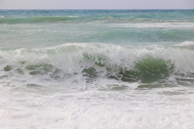 Korfu adasındaki Agios Georgios 'ta fırtınalı bir günde dalgaların çarptığı mavi ve yeşil renkli deniz.