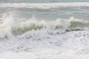 Korfu adasındaki Agios Georgios 'ta fırtınalı bir günde dalgaların çarptığı mavi ve yeşil renkli deniz.