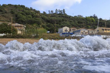 Korfu adasındaki Agios Georgios 'ta fırtınalı bir günde dalgaların çarptığı mavi ve yeşil renkli deniz.