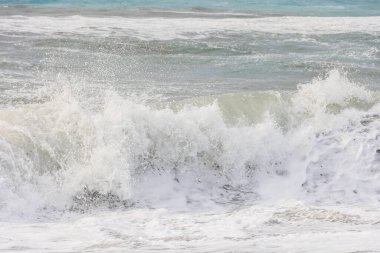 Korfu adasındaki Agios Georgios 'ta fırtınalı bir günde dalgaların çarptığı mavi ve yeşil renkli deniz.
