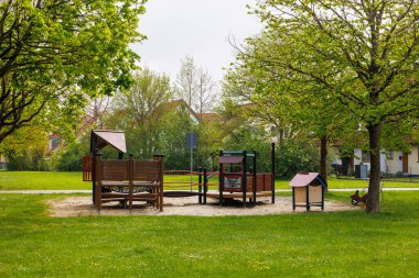 Parlak kırmızı oyun kulesi olan bir oyun alanı ve bulutlu bir günde Augsburg, Bavyera yakınlarındaki Konigsbrunn 'da kayıyor.