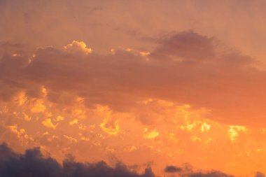 Colourful sunset in the bay of Agios Georgios with dark clouds in front of an intensely orange sky with individual strangely shaped dark wispy clouds on the island of Corfu clipart