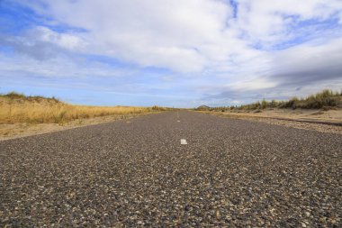 Petten aan Zee 'deki Hollanda sahillerine giden yol rüzgarlı bir günde bulutlu bir gökyüzü ile