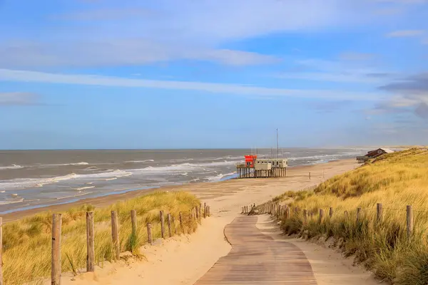 stock image Footpath to the beach with a lifeguard house on a stormy day with cloudy skies in Petten aan Zee in the Netherlands