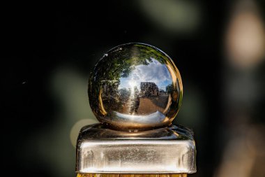 Ahşap bir çit direğinin ucu gibi parlak krom bir top bulanık bir arka plana karşı