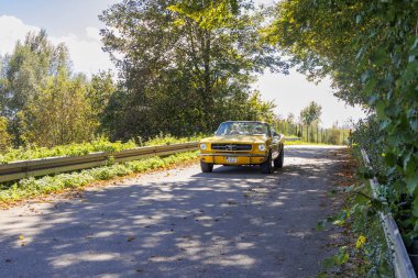 Sarı Ford Mustang GT 1966 'dan kalma üstü açık Radom in Raisting am Ammersee' nin önündeki otoparkta Eski Zaman Fuggerstadt Klasikleri 'nde mavi gökyüzünün altında, Almanya' da Raisting 29.2024