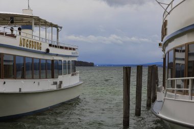Almanya, Stegen, 03-26-2023, Ammersee iskelesi Stegen am Ammersee 'de yolcu gemileriyle kışın bulutlu bir havada.