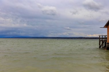 Bulutlu bir günde Ammersee 'ye bak.