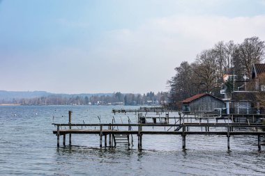 Bavyera 'daki Seeshaupt' taki kayıkhaneler ve iskeleler hafif bulutlu bir kış gününde Starnberg Gölü 'nde.