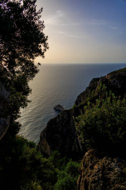 Güneş, Agios Spiridon yakınlarındaki Agios Spiridon adasında sahil siluetine karşı altın renginde batıyor.