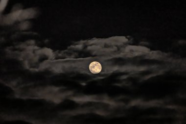 Dolunay karanlık gökyüzünde dramatik gece bulutlarında parlıyor.