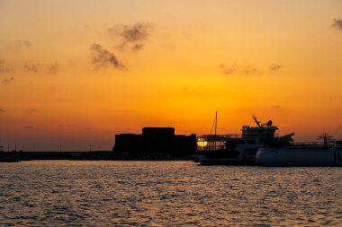Paphos Kalesi ve limanı üzerinde altın gün batımı, Kıbrıs, 23.11.2024.