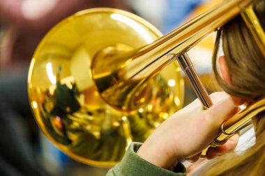 Altın pirinçten enstrümanı olan trombon çalıcısı, çan üzerinde yansımaları olan yakın çekim görüntüsü