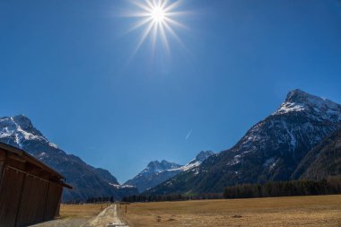 Karlı dağ sırası ve kırsal yol olan Otztal, Avusturya 'nın Alp Dağları üzerindeki güneş ışığı