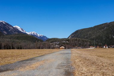 Karlı dağlık yamaçlar, açık bahar gökyüzü altındaki yerleşim evleri, Otztal, Avusturya